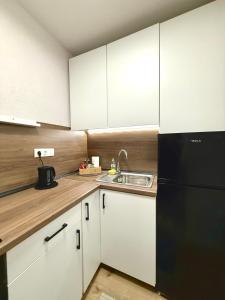 a kitchen with white cabinets and a black refrigerator at Studio Apartment 1906 in Mostar