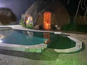 a house with a swimming pool in front of a building at NiMo Bamboo in Jimbaran