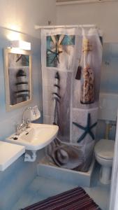 a bathroom with a sink and a toilet with a shower curtain at Roptro Rooms in Parga