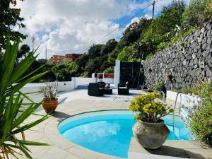 una piscina en un patio con plantas y una pared de piedra en Lightbooking Panchita Villa de Mazo Piscina, en Mazo