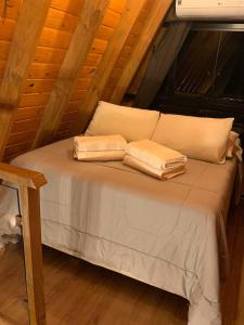 a bed with two pillows on it in a attic at Cabana Amélia, em Gramado in Gramado