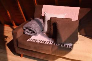 a brown chair with two pillows and a blanket at Cabana Amélia, em Gramado in Gramado