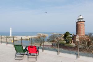two chairs sitting on a ledge with a lighthouse at Jantar Apartamenty Deluxe Sea View in Kołobrzeg