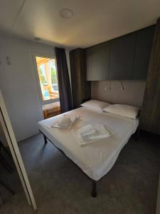 a bedroom with a bed with white sheets and a window at Mobile home Lučica in Drage