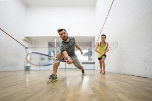 a man and a woman playing a game of tennis at Amenity Hotel & Resort Lipno in Lipno nad Vltavou