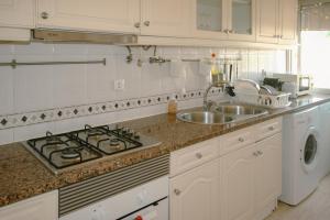 a white kitchen with a sink and a stove at Queluz Apartment in Queluz