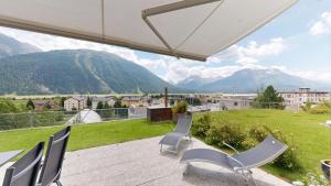 a patio with chairs and a view of mountains at Apartment Quadratscha in Samedan