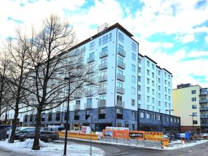a large blue building with snow on the ground at Kotimaailma Apartments - keskustayksiö - Aleksanterinkatu in Tampere