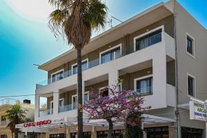 a white building with a palm tree in front of it at Cozy Studio #10 in Malia
