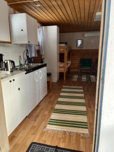 a kitchen with white cabinets and a wooden floor at Kolbackens Camping & Stugby in Åsarne +9 photos
