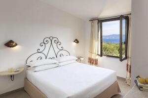 a bedroom with a large white bed with a window at Residence Il Mirto in Palau +18 photos