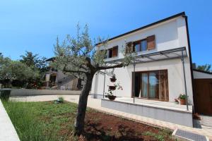 a white house with a tree in the yard at Studio Rovinj Home in Rovinj