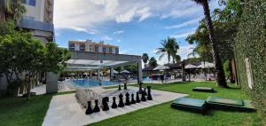 a resort with a pool and giant chessboards in the grass at Le Jardin Suites Luxo - Central de Reservas in Caldas Novas