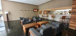 a waiting room with blue chairs and a bar at Le Jardin Suites Luxo - Central de Reservas in Caldas Novas