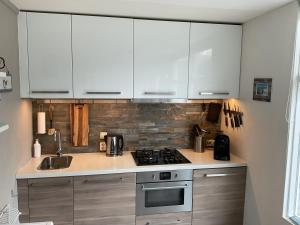 a kitchen with white cabinets and a stove at Appelbloesem in Bergen