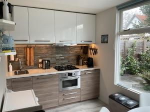 a kitchen with white cabinets and a stove and a window at Appelbloesem in Bergen