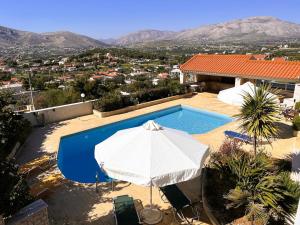 a swimming pool with an umbrella and a house at Bella Vista pool Villas in Anavissos in Barbaliáki