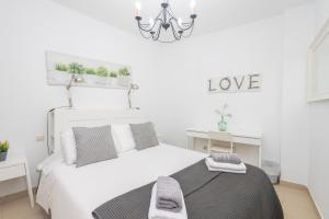 Habitación blanca con cama y lámpara de araña. en Lightbooking Tazacorte La Palma, en Tazacorte