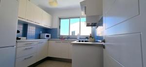 a white kitchen with white cabinets and a window at Vv BRISAMAR in Telde