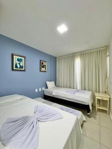 two beds in a room with blue walls at Cobertura no Golf Ville deck privativo com jacuzzi e churrasqueira in Berra Bode