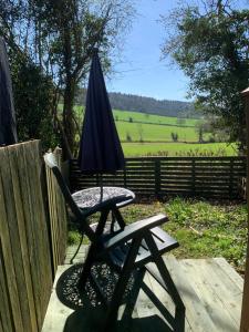 a chair with an umbrella sitting on a patio at Hedgehog Lodge in Colwall