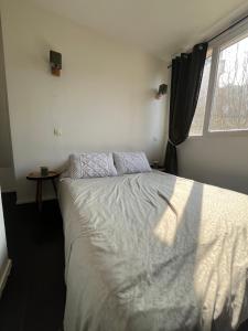 Appart au pied du T2 La Défense Paris في بيزونس: غرفة نوم بسرير أبيض مع نافذة