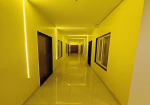 a hallway with yellow walls and a long hallway with paintings at Hotel R.Raghavam in Ayodhya