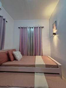a bedroom with a bed and a window with curtains at Rapha's Place Joy - A in Bacolod