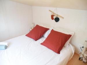 a white bed with two red pillows on it at Charmante tiny house avec baie extérieure et kota grill à Manoncourt-en-Vermois - FR-1-584-374 in Manoncourt-en-Vermois