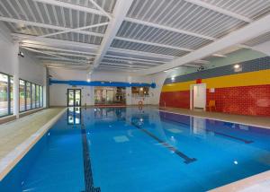 a large indoor swimming pool with blue water at Fell End in Milnthorpe