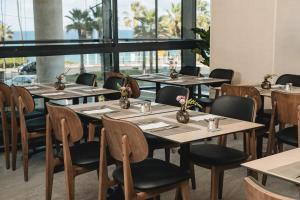 eine Reihe von Tischen in einem Restaurant mit Fenstern in der Unterkunft Almera Hotel in Bat Yam
