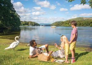 a group of people sitting on the grass near a lake at Crake Valley in Torver