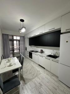 a kitchen with white cabinets and a table and a dining room at Nazz in Bishkek