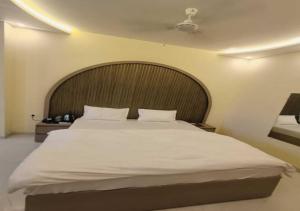 a bedroom with a large bed with a wooden headboard at Hotel R.Raghavam in Ayodhya