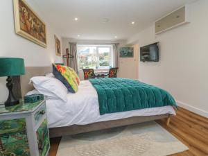 a bedroom with a bed with a green blanket on it at Elder Cottage Studio in Truro