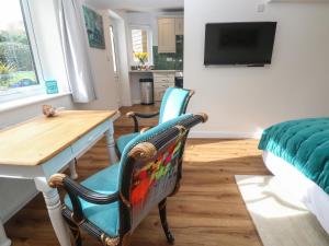 a living room with a table and two chairs and a television at Elder Cottage Studio in Truro