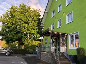 a green building with a car parked in front of it at Haus Thal in Overath