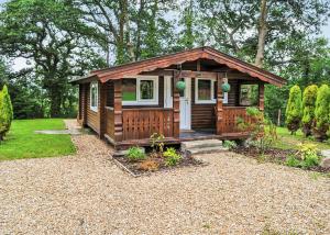 a small wooden cabin with a porch in a garden at Heronstone Lodges in Ystalyfera