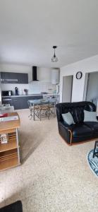 a living room with a black couch and a kitchen at Appartement au coeur du perche in Val-au-Perche
