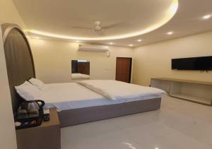 a bedroom with a bed and a flat screen tv at Hotel R.Raghavam in Ayodhya