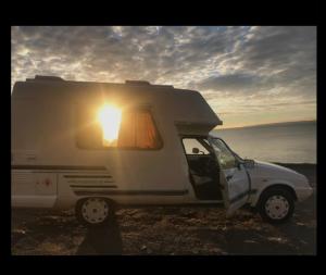 un camper bianco con la porta aperta e il sole splendente di Romahome double camper with Sea View a Porthleven