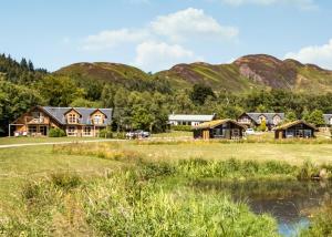 a group of houses with mountains in the background at Loch Lomond Waterfront Luxury Lodges in Balmaha