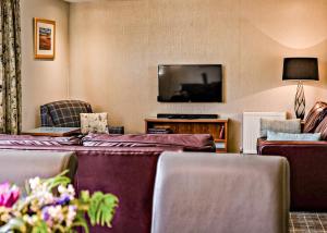 a hotel room with a bed and a flat screen tv at Loch Lomond Waterfront Luxury Lodges in Balmaha