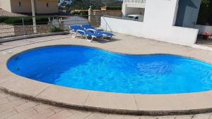a large blue swimming pool with blue chairs next to a house at Ola Somhome in Peniscola