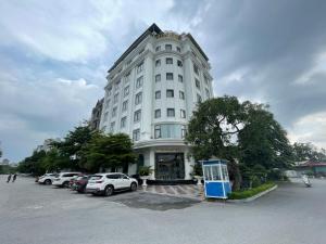a white building with cars parked in a parking lot at Lotus Hotel & Apartment in Hai Phong +30 photos