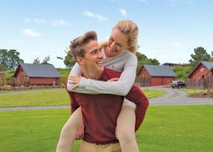 un homme portant une femme sur son dos dans l'établissement Nunland Hillside Lodges, à Lochfoot