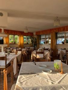 a restaurant with white tables and chairs and windows at Hotel Lory in Garda