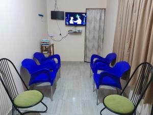 a waiting room with blue chairs and a tv at Sunshine Guest House in Kataragama