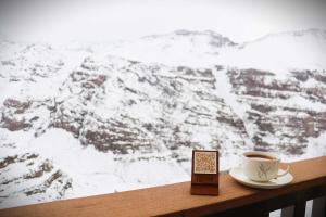 a cup of coffee sitting on a table with a snow covered mountain at HOM I Departamento en Valle Nevado Amplio Dúplex 6PAX SKIOUT in Farellones +36 photos