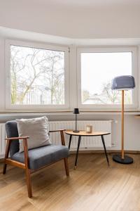 a living room with a chair and a table and two windows at 1 bedroom flat 55m2 in the city in Luxembourg